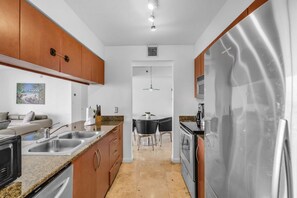 A modern kitchen with granite countertops, stainless steel appliances, and wooden cabinets. - Panoramic 2BR Bay-View in Brickell With Parking (Miami)