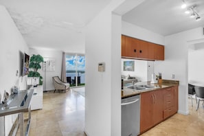 A modern kitchen with wooden cabinets, a built-in dishwasher, and a large window offering a view.