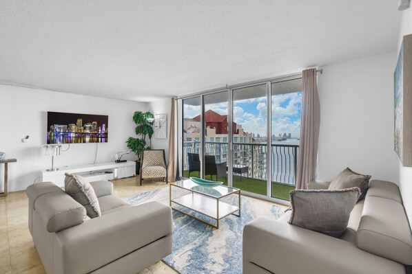 A modern living room with a large sliding glass door leading to a balcony with a city view.