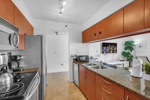 A modern kitchen with stainless steel appliances, a granite countertop, and wooden cabinets.