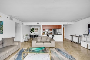 A modern living room with a sofa, coffee table, and a dining area with chairs and a table.