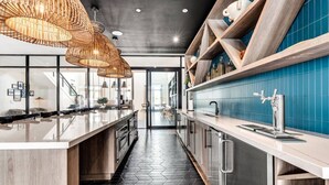 Una cucina moderna con isola centrale, zoccolo a mosaico scuro e lampadario a sospensione.
