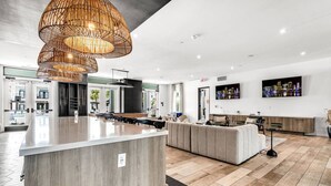 Una cucina moderna con un'isola grande, un'area pranzo con divano e una TV a parete.