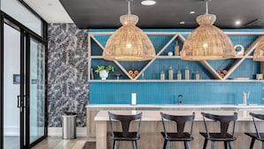 Una cucina moderna con rivestimento blu, parete a motivi bianchi e neri e tre lampade a sospensione.