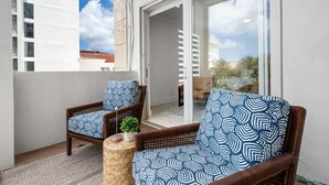 Un balcón con dos sillones de mimbre, una mesita y una planta en maceta.
