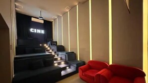 A modern cinema room with a red sofa, a staircase leading to a darkened area labeled "CINE", and a minimalist design with vertical light strips.