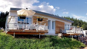 A modern house with a balcony, wooden deck, and outdoor seating area.