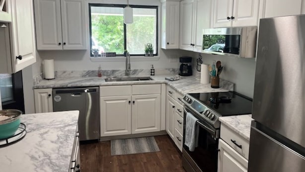 Una cocina moderna con gabinetes blancos, un refrigerador de acero inoxidable, un microondas y una estufa.