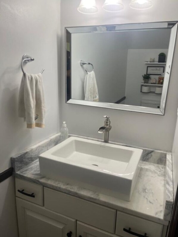 A bathroom with a white sink, a mirror, and a towel rack.