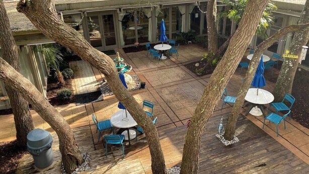 Un área de patio al aire libre con piso de madera, sillas azules y sombrillas.