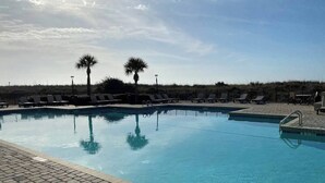Una piscina con sillas de descanso y palmeras.