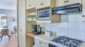 A compact kitchen with a microwave, coffee maker, and gas stove.