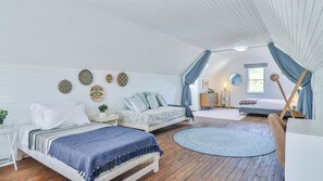 A cozy bedroom with two beds, a round rug, and a window with curtains. - Plover Place | Coastal Nr Breakfast Bays Pools (Vermont)