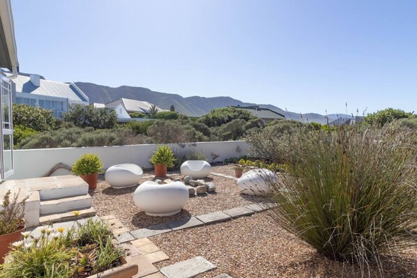 A rooftop garden with potted plants, seating areas, and a view of distant mountains.
