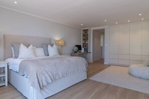 A bedroom with a large bed, bedside table, lamp, and a wardrobe.