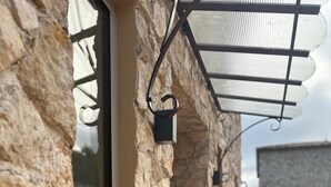 Un bâtiment en pierre avec une porte en verre et un auvent en métal.
