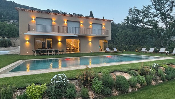 Une maison moderne à deux étages, dotée d’une piscine, d’un espace salon extérieur et d’un jardin bien entretenu.