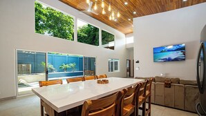 Une cuisine moderne dotée d’un grand îlot central, de chaises en bois et d’un four encastré.