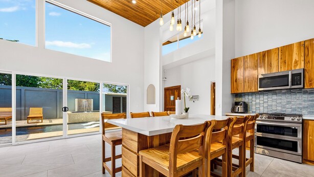 Une cuisine moderne avec des meubles en bois, un grand îlot central et un coin repas avec des chaises.