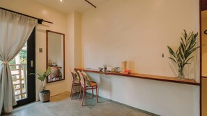 A modern room with a wooden reception desk, a potted plant, a chair, and a large mirror on the wall. - UNLTD Hotel Siargao (General Luna)