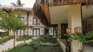 A courtyard with a thatched roof, potted plants, and a staircase leading to an upper level. - UNLTD Hotel Siargao (General Luna)