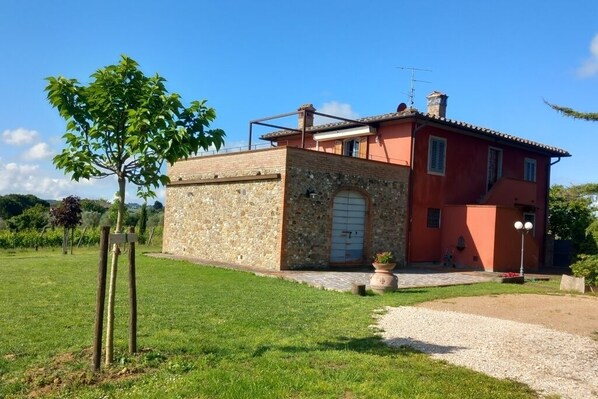 Una casa de dos pisos con fachada de piedra y ladrillo, un pequeño jardín y un cielo despejado.
