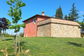 Un edificio de piedra con fachada roja y una pequeña construcción adosada.