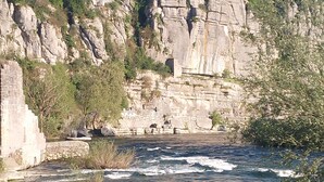 A river flowing through a rocky landscape with cliffs and sparse vegetation. - In the heart of the Ardeche river (Vogüé)