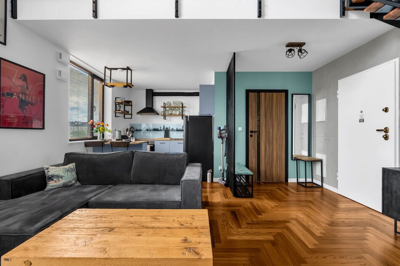 A modern living room with a sofa, a wooden coffee table, and a kitchen in the background.