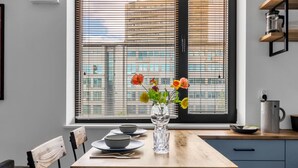 Una cocina con una mesa de madera, dos cuencos, un florero con flores y una cafetera sobre la encimera.