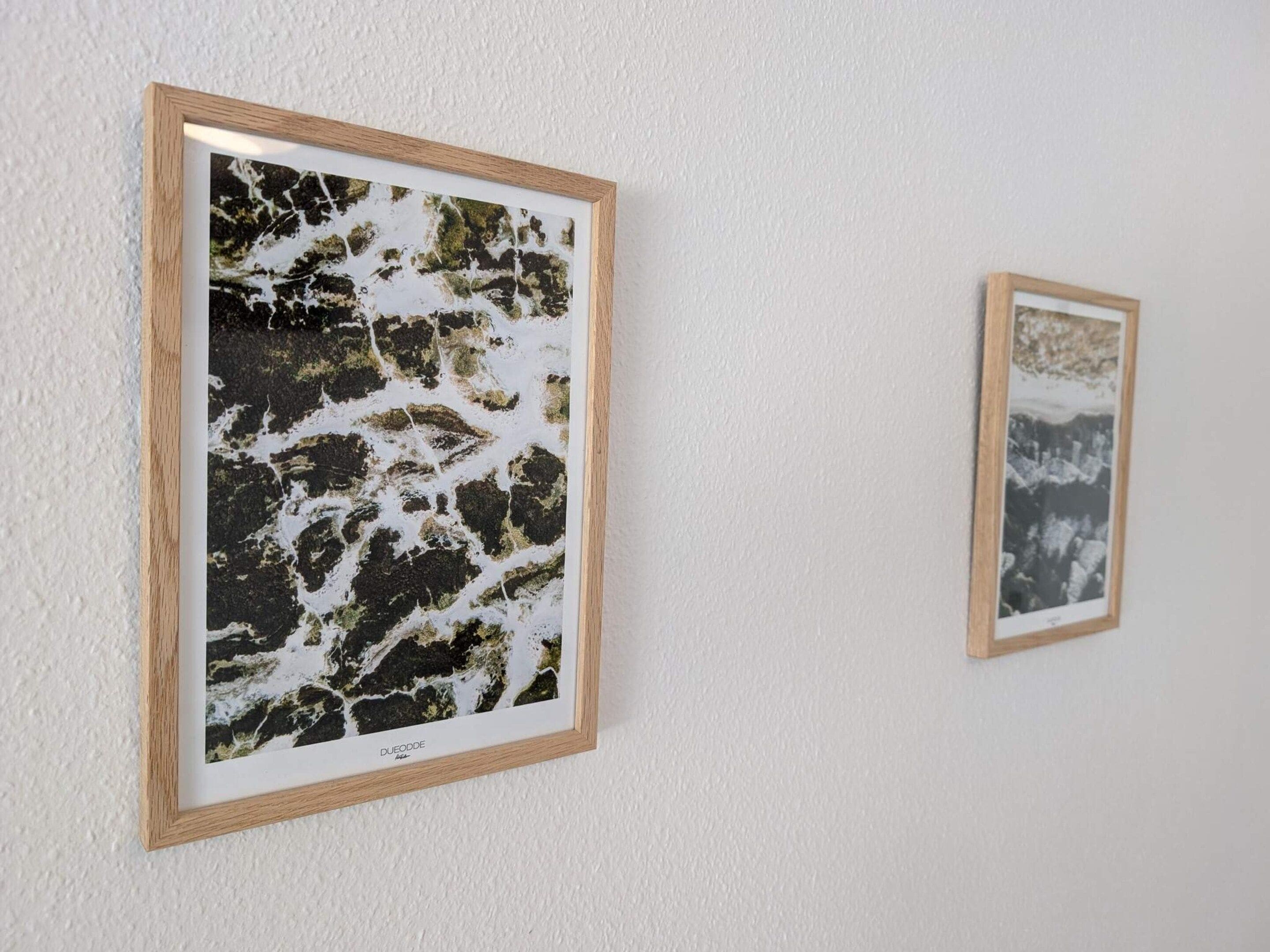 Two framed artworks on a white wall.