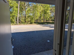 A view through a door into a parking area with trees in the background.