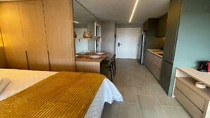 Ein Hotelzimmer mit Bett, einem Holzschrank, einer Küchenzeile und einem Essbereich.