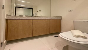 Ein modernes Badezimmer mit einem Holzlagerfläschchen, einem großen Spiegel und einer weißen Toilette.