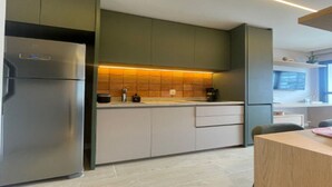 Eine moderne Küche mit Einbaukühlschrank, einer Arbeitsplatte mit Wasserkocher und einem Holzespeisetisch.