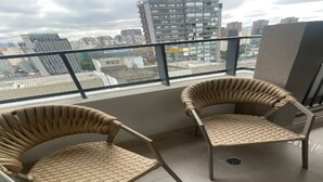 Ein Balkon mit zwei Korbstühlen und Blick auf die Stadtlandschaft.