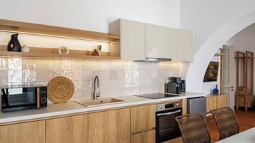 Una cocina moderna con armarios de madera, horno empotrado, microondas y cafetera.