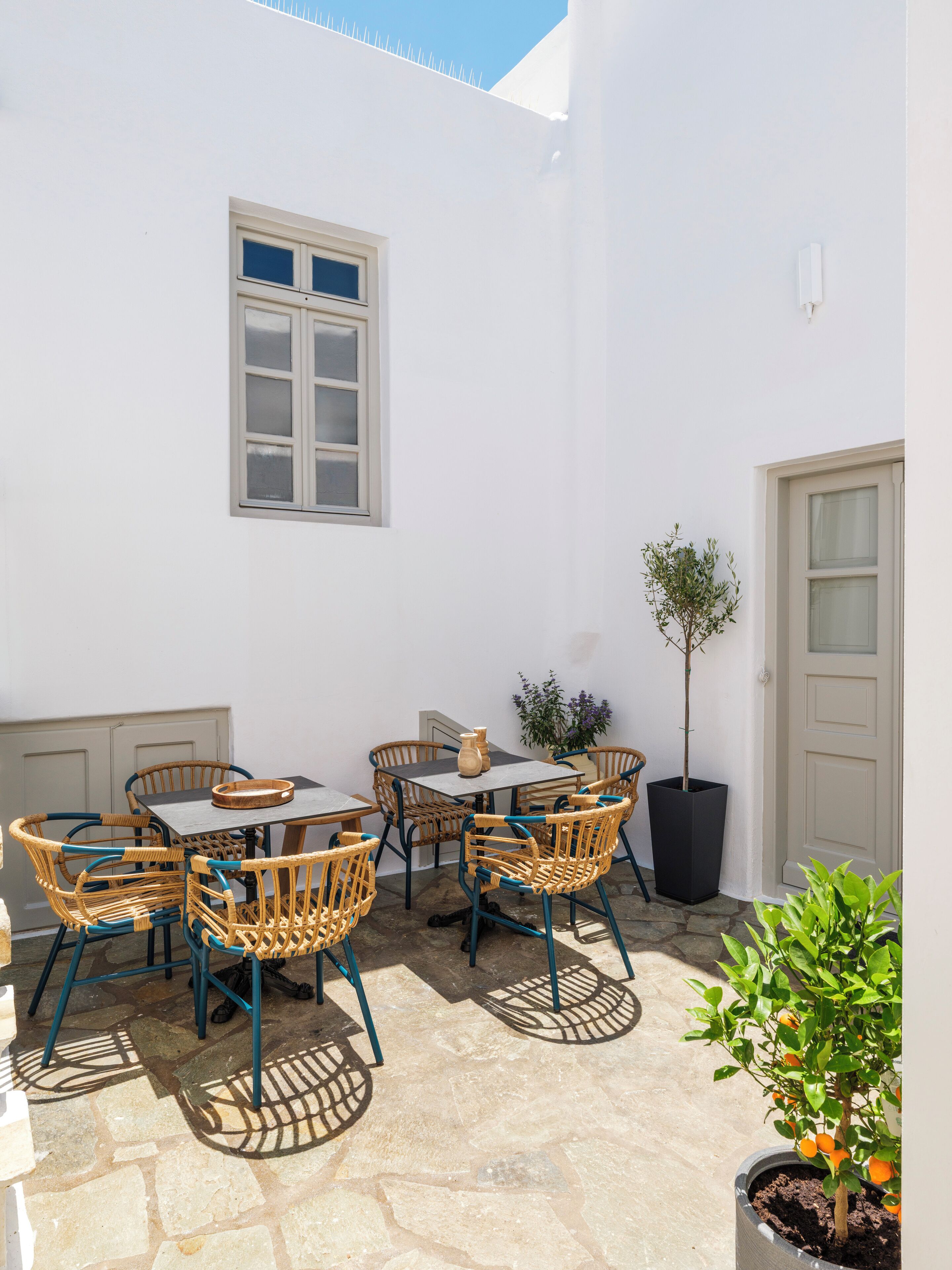 Eine Terrasse mit Tisch, Stühlen, einem Blumentopf und einer Tür.