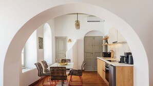 Una cocina moderna con una isla central, suelo de madera y una zona de comedor con sillas de mimbre.