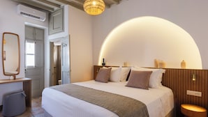 Un dormitorio con una cama grande, una mesita de noche, un espejo, una lámpara colgante y techo de madera.