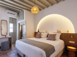 Quarto com cama grande, mesa de cabeceira, espelho, luminária pendente e teto de madeira.