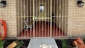 Entrada de un edificio con una reja metálica, paredes de ladrillo y el número '2016' sobre la puerta.
