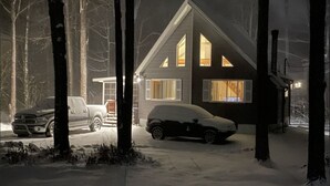 A house with a sloped roof, large windows, and a garage.