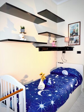Un dormitorio con una cama, una cuna, estantes en la pared y una foto enmarcada.