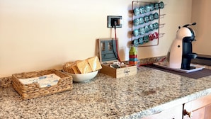 A kitchen with wooden cabinets, a granite countertop, a coffee maker, and a basket of bread. - Cozy vacation apartment (Rapallo)