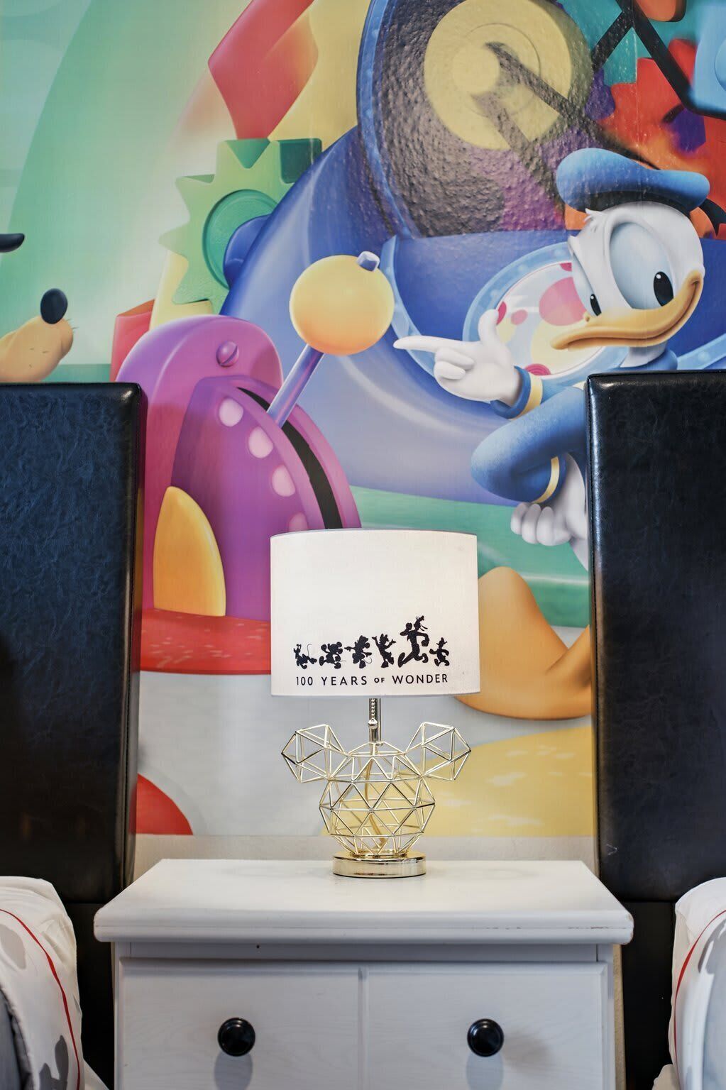 A room with a colorful mural, a white cabinet with a geometric light fixture, and a sign with Chinese characters.