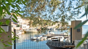 Un barbecue sur un balcon donnant sur une marina remplie de bateaux.
