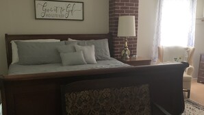 Un dormitorio con cama, una silla, una lámpara y una pared con una cita motivacional.