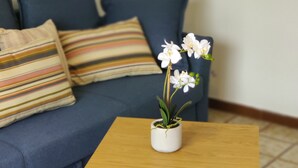 A small wooden table with a potted orchid in the center, placed on a tiled floor. - Peaceful Lakefront (Vello)