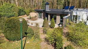 A modern house with a large garden, a gazebo, and a solar panel.